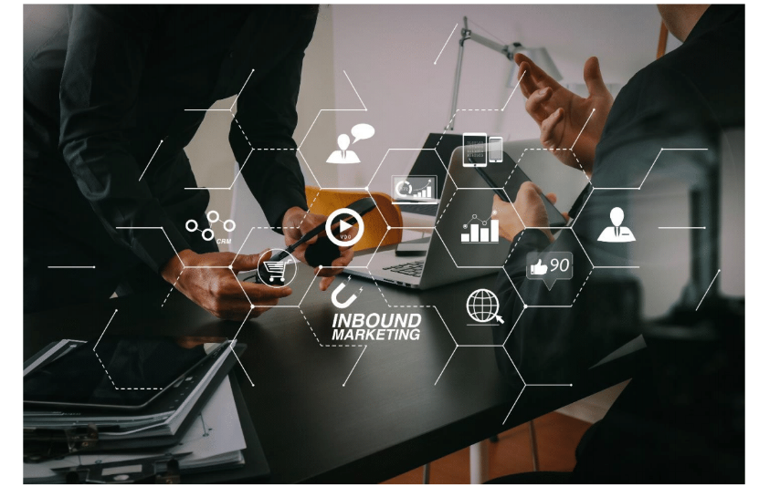 Profesionales analizando estrategias digitales sobre un escritorio con gráficos e iconos digitales de Inbound Marketing superpuestos.
